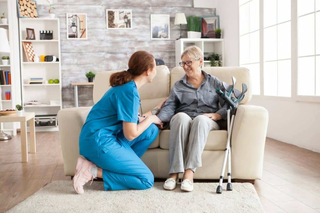 Healthcare worker in blue scrubs assisting elderly patient in medical clinic setting.